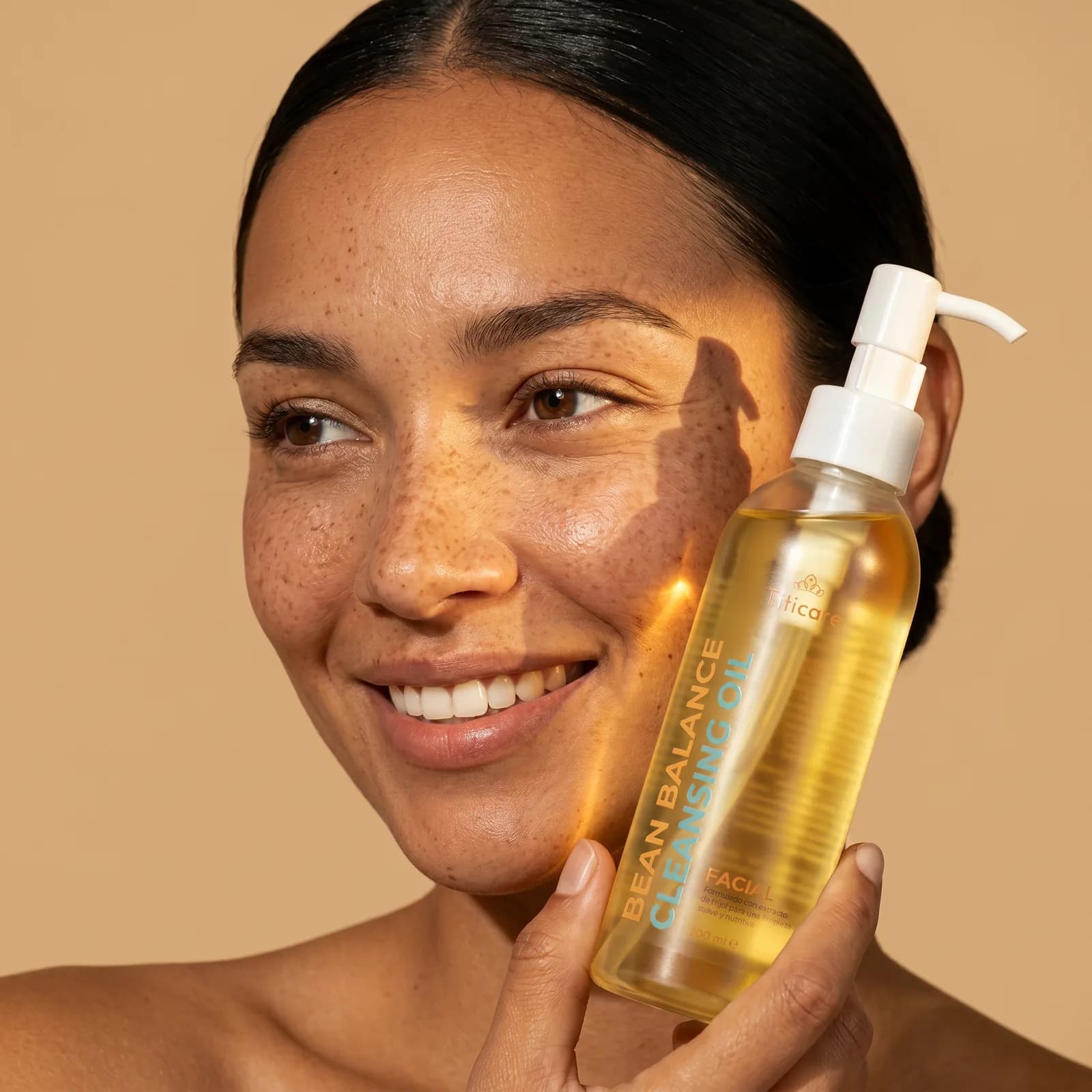 Smiling model holding the Titicare cleansing oil bottle in warm directional light