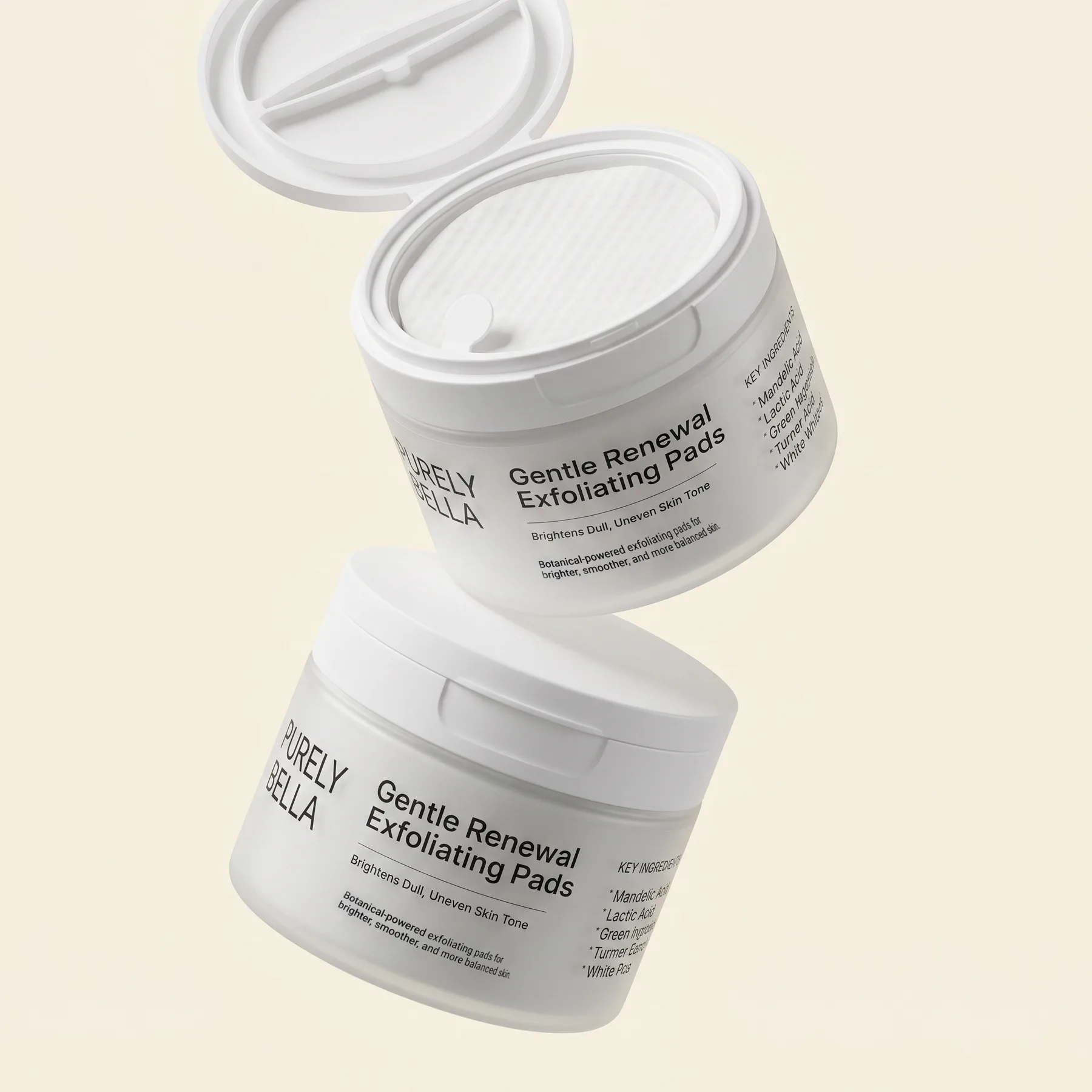 Two Purely Bella Gentle Renewal Exfoliating Pads jars floating on cream, the upper one open with its lid tilted back
