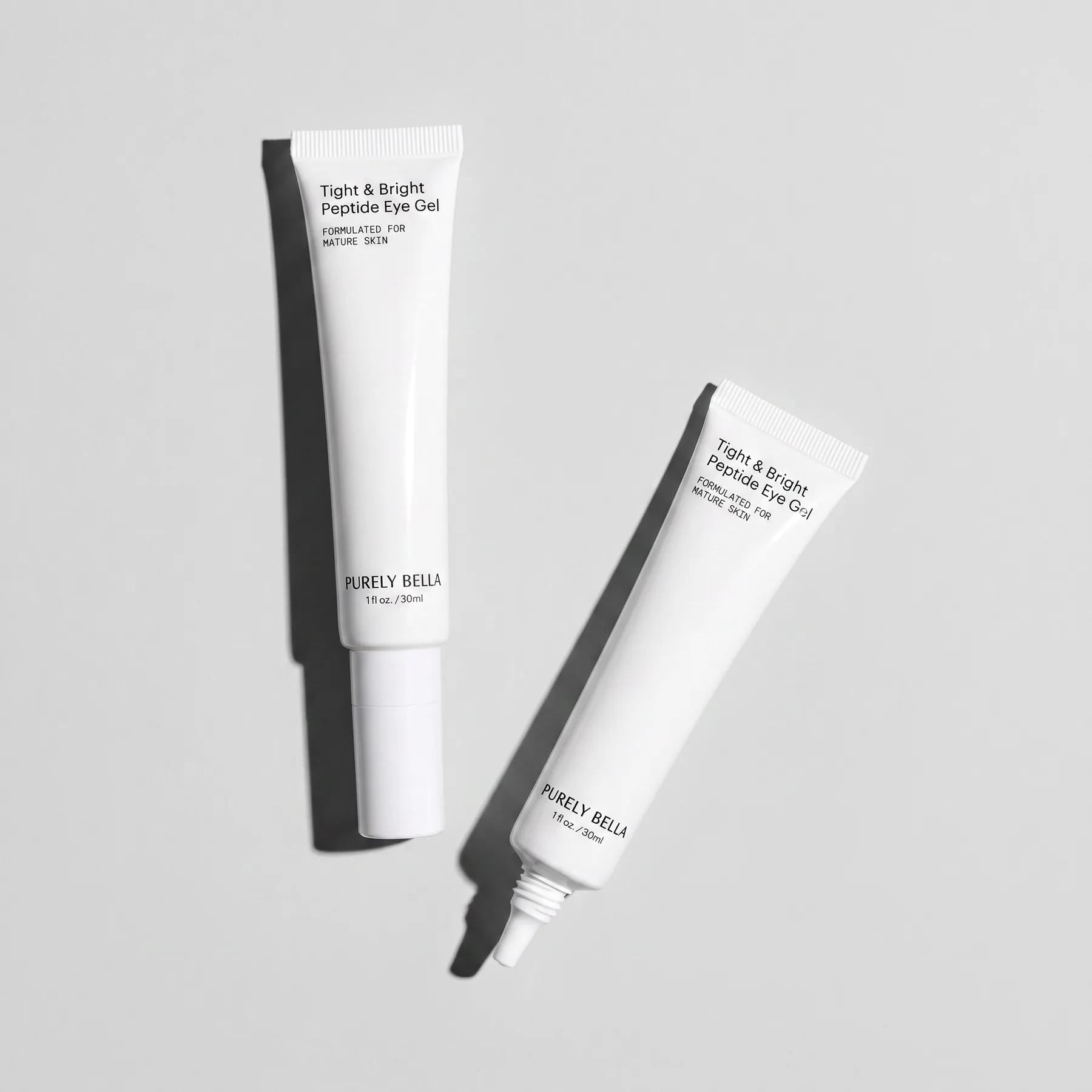 Two Purely Bella Tight & Bright Peptide Eye Gel tubes arranged diagonally on grey
