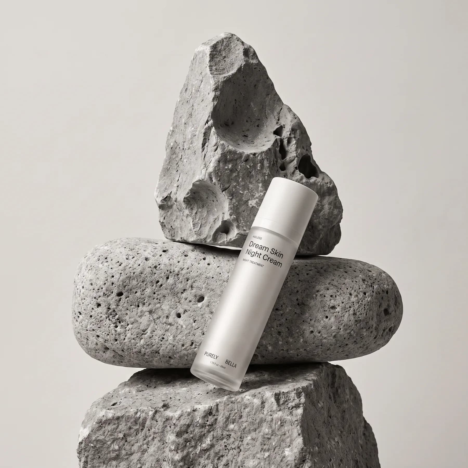 Purely Bella Dream Skin Night Cream leaning on a stack of grey volcanic stones