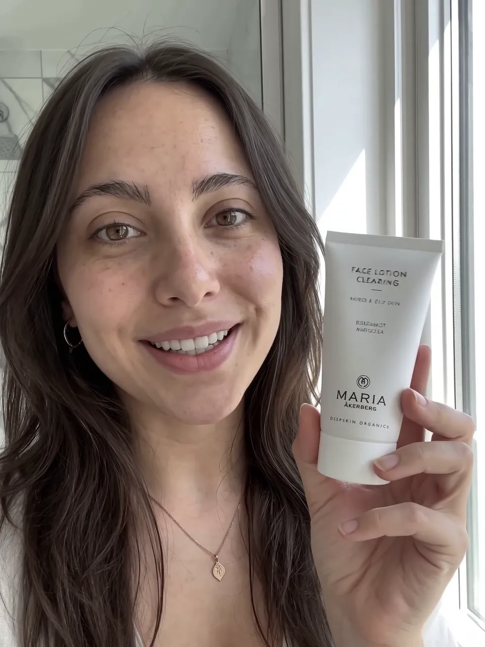 Creator smiling to camera and holding up the Face Lotion Clearing tube, frame from the AI UGC sample